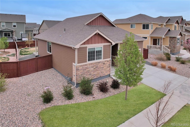 1867 Abundance Dr, Windsor, CO 80550 - view of front of house featuring board and batten siding, a residential view, fence, concrete driveway, and stone siding