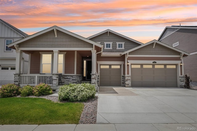 12841 Lake Port St, Longmont, CO 80504 - craftsman-style home with covered porch, driveway, stone siding, a garage, and a front yard