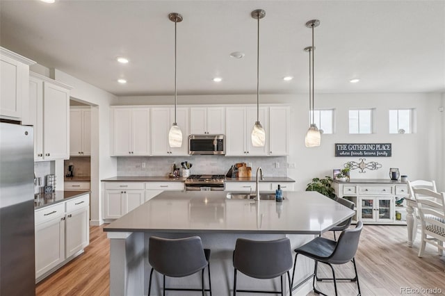 12841 Lake Port St, Longmont, CO 80504 - kitchen with stainless steel appliances, tasteful backsplash, recessed lighting, a breakfast bar area, and white cabinetry