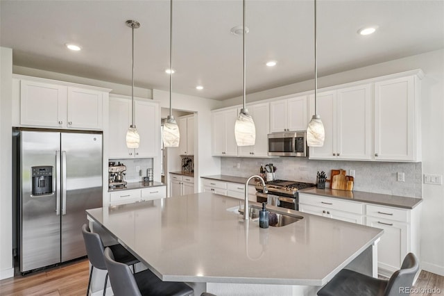 12841 Lake Port St, Longmont, CO 80504 - kitchen featuring stainless steel appliances, a breakfast bar, tasteful backsplash, light wood-type flooring, and recessed lighting