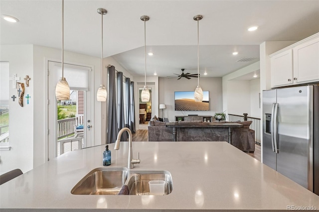 12841 Lake Port St, Longmont, CO 80504 - kitchen featuring stainless steel fridge, a kitchen island with sink, ceiling fan, white cabinetry, and light countertops
