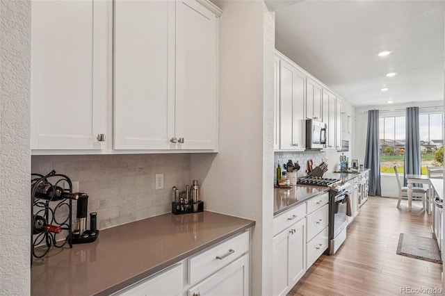 12841 Lake Port St, Longmont, CO 80504 - kitchen featuring appliances with stainless steel finishes, backsplash, white cabinets, recessed lighting, and dark countertops