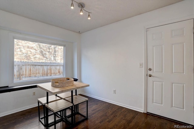 dining area featuring dark wood-style flooring and baseboards