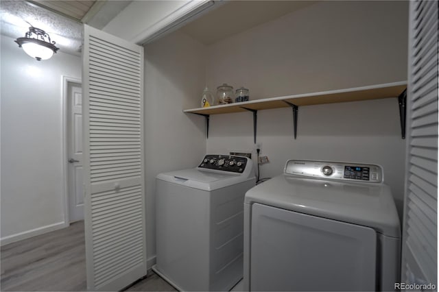 laundry room with baseboards, light wood finished floors, separate washer and dryer, and laundry area