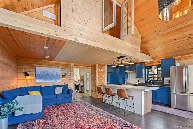 living room with wooden walls, visible vents, and wood ceiling