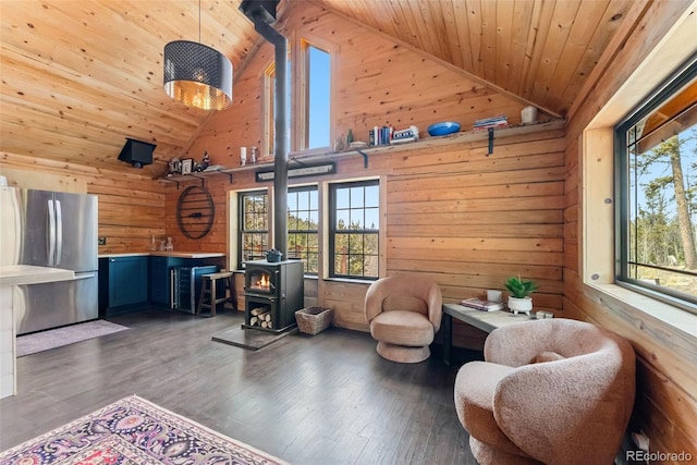 living area featuring wooden walls, a wood stove, a wealth of natural light, and wood ceiling