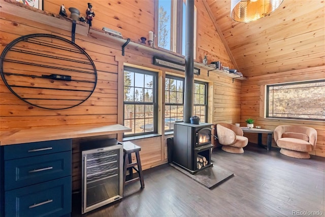 interior space featuring wine cooler, a wood stove, wooden walls, and vaulted ceiling
