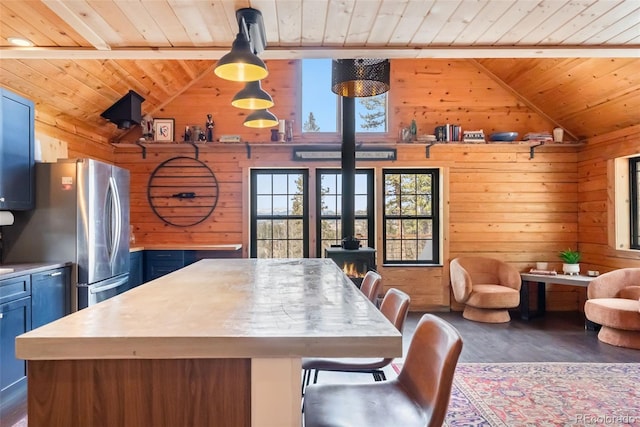 kitchen with wooden walls, vaulted ceiling, freestanding refrigerator, and blue cabinetry