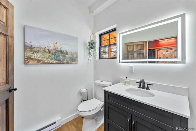 bathroom featuring vanity, toilet, wood finished floors, a baseboard heating unit, and baseboards