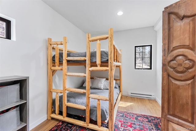 bedroom featuring a baseboard radiator, wood finished floors, baseboards, and recessed lighting