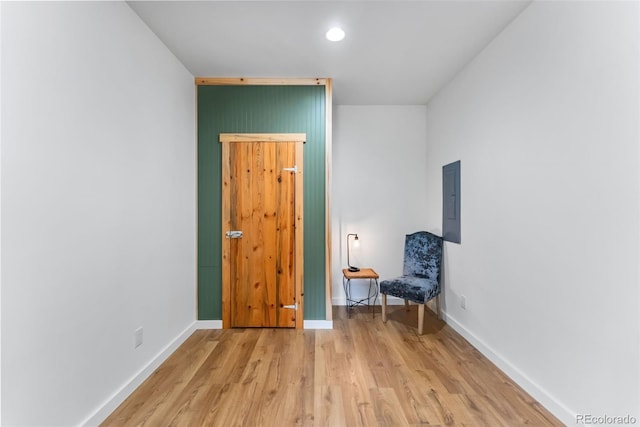 unfurnished room featuring electric panel, light wood finished floors, and baseboards