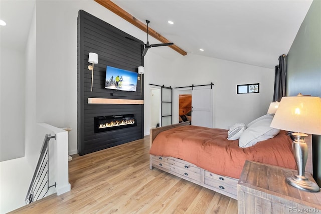bedroom featuring a large fireplace, vaulted ceiling, recessed lighting, a barn door, and wood finished floors