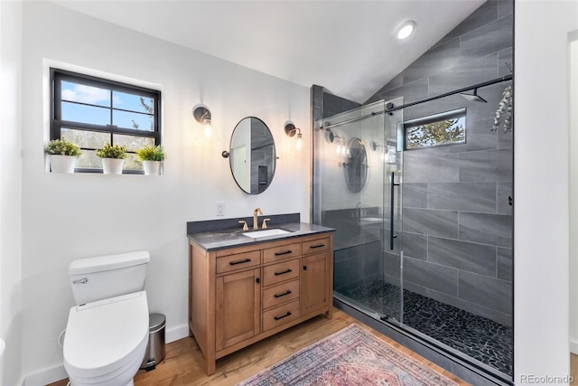 bathroom with a shower stall, vanity, vaulted ceiling, toilet, and wood finished floors