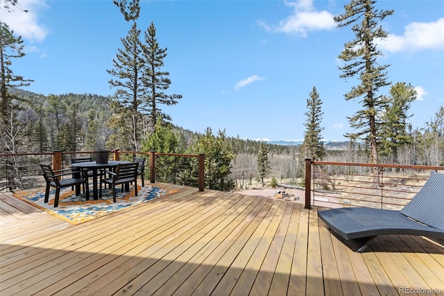 wooden deck with a wooded view and outdoor dining space