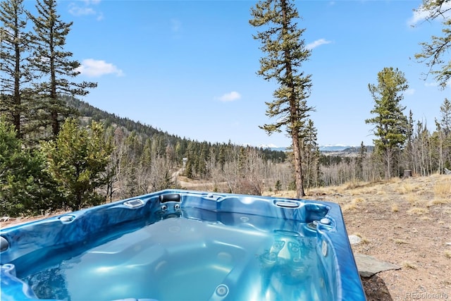 view of swimming pool featuring a mountain view, a forest view, and a hot tub