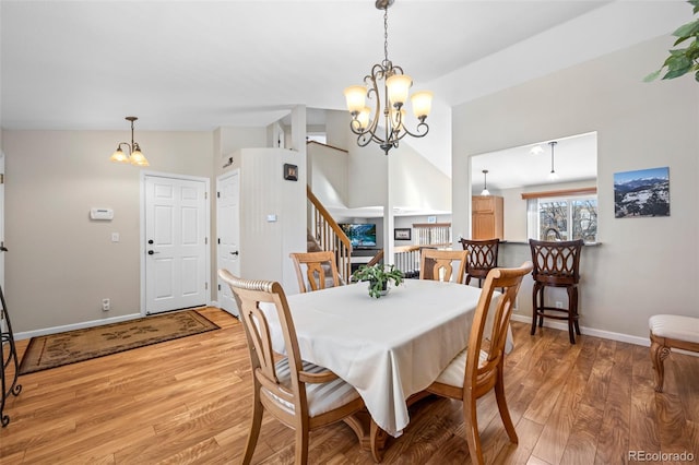 dining space with an inviting chandelier, lofted ceiling, and light hardwood / wood-style floors