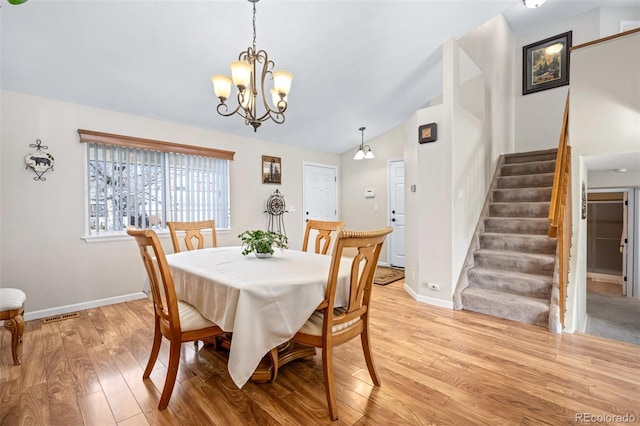 dining room featuring lofted ceiling, an inviting chandelier, and light hardwood / wood-style floors