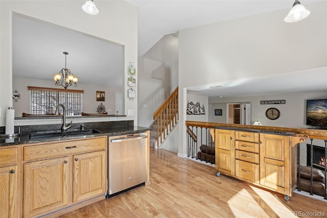 kitchen featuring sink, dark stone countertops, hanging light fixtures, stainless steel dishwasher, and light hardwood / wood-style floors