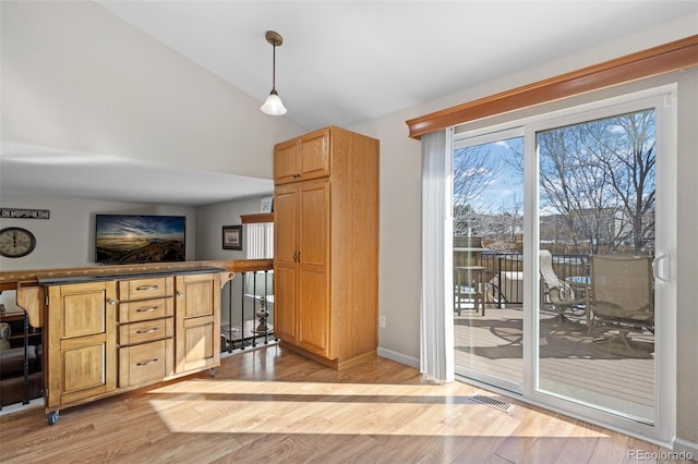 interior space featuring vaulted ceiling, pendant lighting, and light hardwood / wood-style flooring