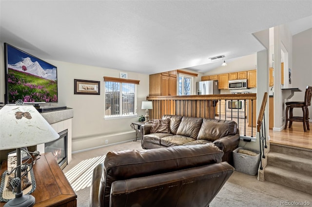 carpeted living room with lofted ceiling, a tile fireplace, and a textured ceiling