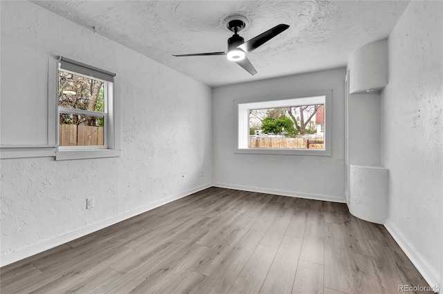 unfurnished room with plenty of natural light, a textured wall, and wood finished floors