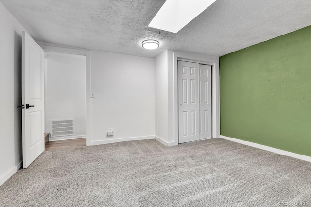 unfurnished bedroom featuring carpet flooring, a textured ceiling, baseboards, visible vents, and a closet