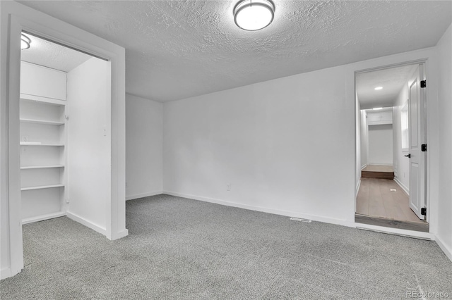 unfurnished bedroom featuring baseboards, carpet flooring, a textured ceiling, and visible vents