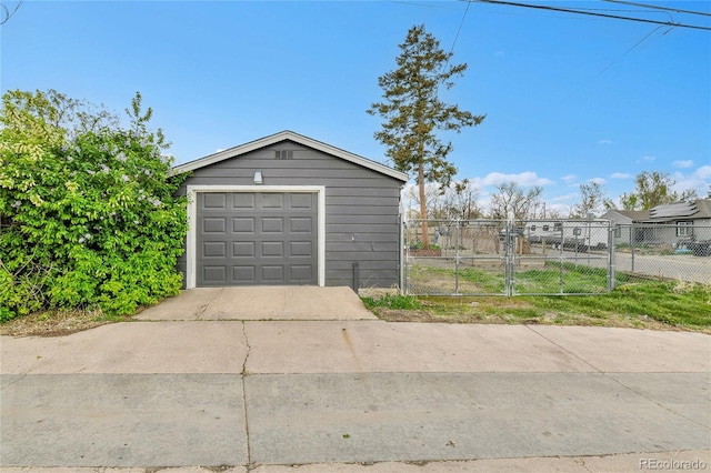 detached garage featuring fence and driveway