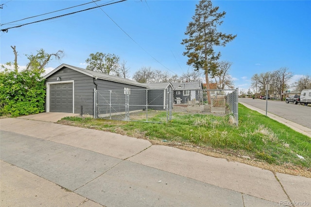 view of front facade featuring a garage, a gate, fence, and an outbuilding