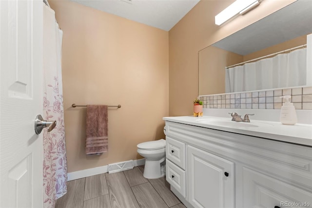 bathroom featuring vanity, backsplash, and toilet