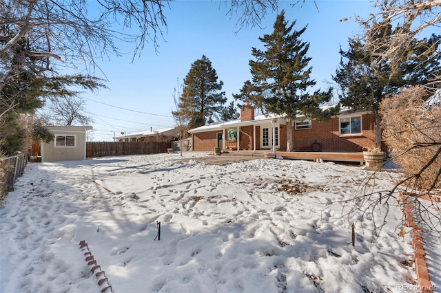 snow covered back of property with a storage unit