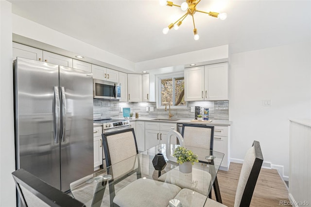 1772 S Pierce St, Lakewood, CO 80232 - kitchen featuring an inviting chandelier, a sink, backsplash, and stainless steel appliances
