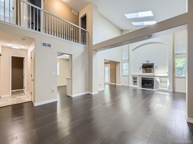 6447 St Vrain Ranch Blvd, Longmont, CO 80504 - unfurnished living room featuring a skylight, wood finished floors, high vaulted ceiling, a fireplace, and baseboards