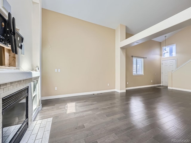 6447 St Vrain Ranch Blvd, Longmont, CO 80504 - unfurnished living room with a brick fireplace, baseboards, wood finished floors, and lofted ceiling