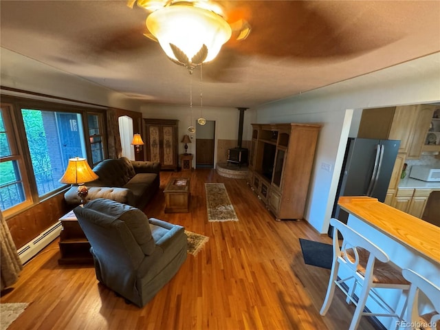 living room featuring hardwood / wood-style flooring, baseboard heating, and a wood stove