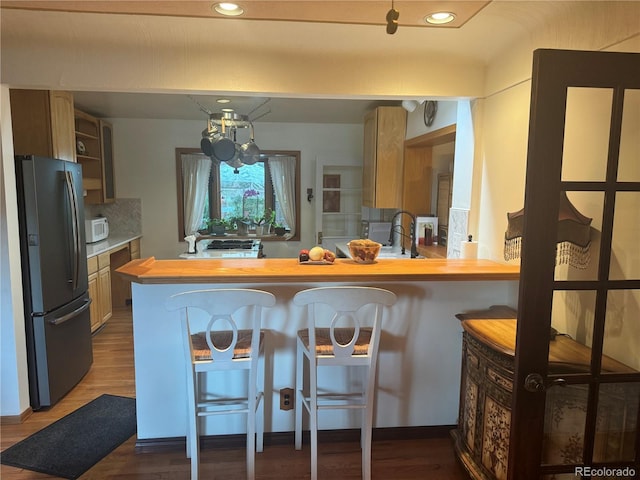 kitchen featuring a kitchen bar, sink, stainless steel refrigerator, and kitchen peninsula