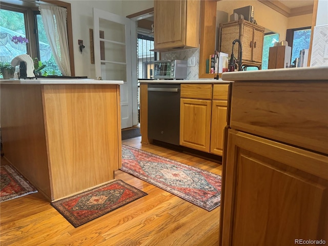 kitchen with stainless steel dishwasher, light hardwood / wood-style floors, and backsplash