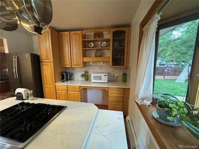 kitchen featuring baseboard heating, appliances with stainless steel finishes, and decorative backsplash