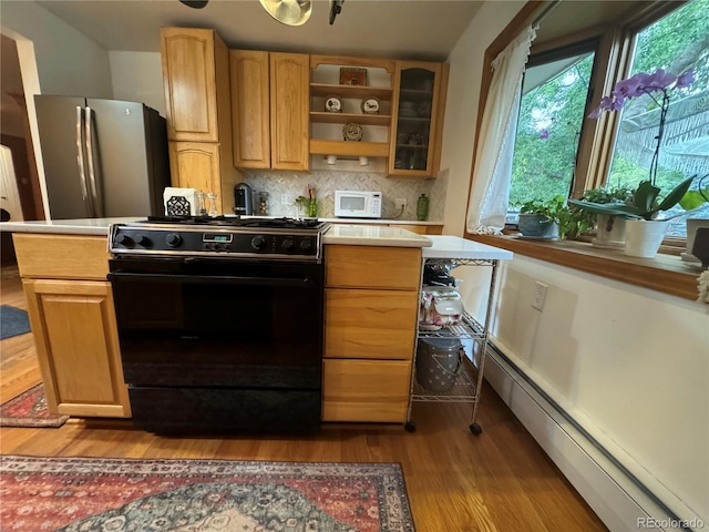 kitchen with stainless steel fridge, backsplash, a baseboard heating unit, black gas stove, and light hardwood / wood-style flooring