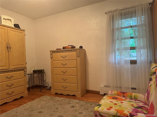 bedroom featuring a baseboard heating unit and light wood-type flooring