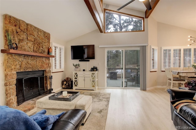 living area with a stone fireplace, wood finished floors, beam ceiling, and a healthy amount of sunlight