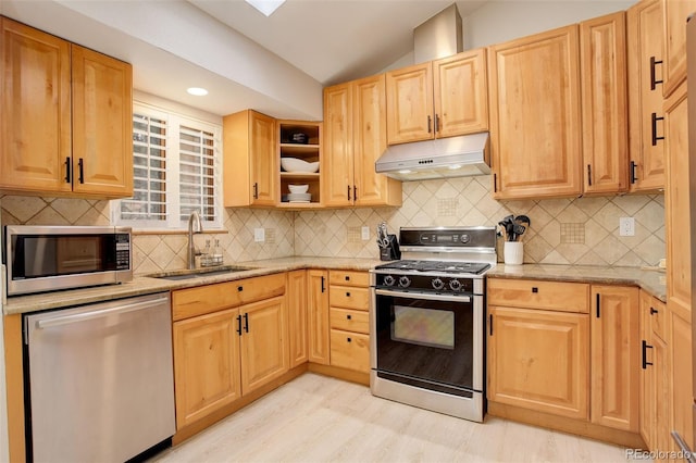 kitchen with appliances with stainless steel finishes, light stone counters, vaulted ceiling, under cabinet range hood, and a sink