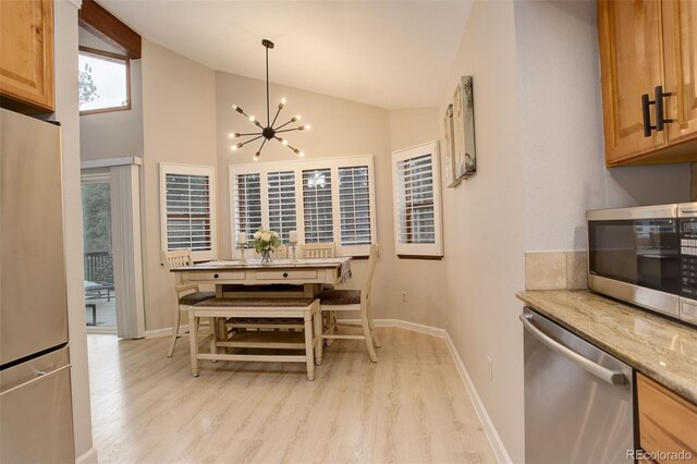 kitchen featuring stainless steel appliances, lofted ceiling, a chandelier, and light wood-style flooring