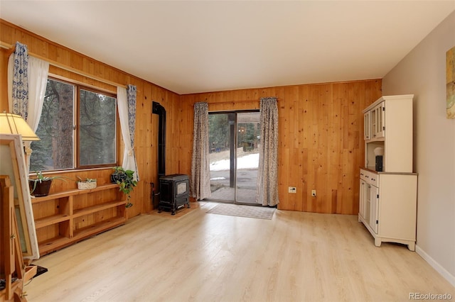 doorway to outside featuring a wood stove, light wood finished floors, and wooden walls