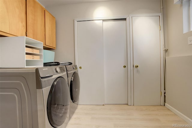 laundry room with light wood-type flooring, independent washer and dryer, and cabinet space