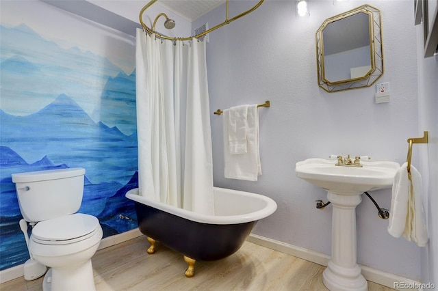 bathroom featuring a washtub, a shower with shower curtain, wood finished floors, and toilet