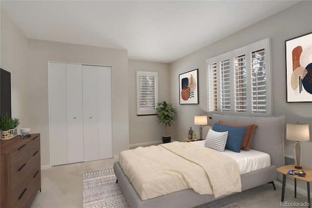 bedroom with light carpet, multiple windows, baseboards, and a closet