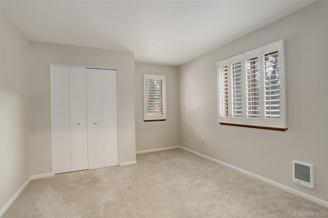 unfurnished bedroom with carpet floors, baseboards, visible vents, and a closet