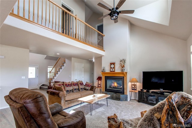 895 Antelope Dr W, Bennett, CO 80102 - living area with high vaulted ceiling, stairs, a ceiling fan, a glass covered fireplace, and baseboards