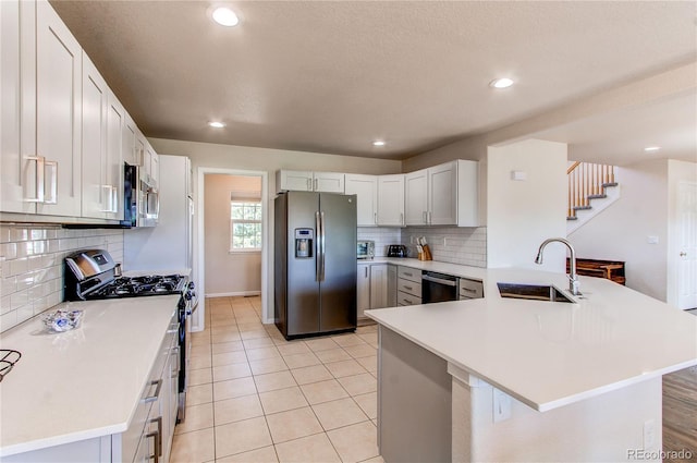 895 Antelope Dr W, Bennett, CO 80102 - kitchen featuring stainless steel appliances, a sink, a peninsula, backsplash, and light countertops